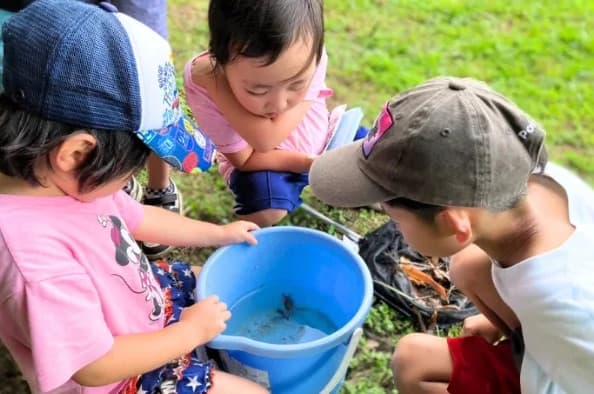 青いバケツを囲んで、なかを覗きこむ子どもたち